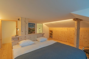 Ein Schlafzimmer mit einem Bett, Nachttischen, einem Spiegel und Holzwänden.