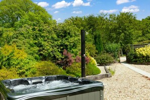 A hot tub in a garden with trees and a gravel path. - Charming Countryside Cottage with Private Hot Tub (Blandford Forum)