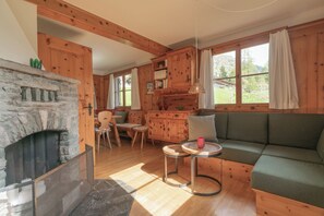 Ein gemütliches Blockhaus-Interieur mit Kamin aus Stein, Holzmöbeln und großen Fenstern.