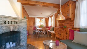 Un intérieur de chalet chaleureux avec une cheminée en pierre, des meubles en bois et un coin repas.