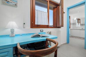 A room with a blue countertop, a wooden chair, a lamp, a window with a curtain, and a view into another room. - 
43
Villa Notte di Stelle, Golfo Aranci, Sardinia (Sardegna)