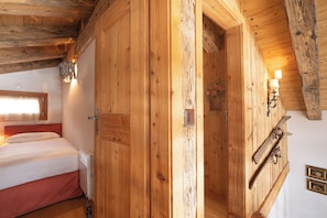 Ein Zimmer mit Holzboden, einem Bett, einem Schrank und einem Skiständer.