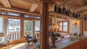 Interior de madeira com cozinha, área de refeições e vista para uma paisagem nevada.