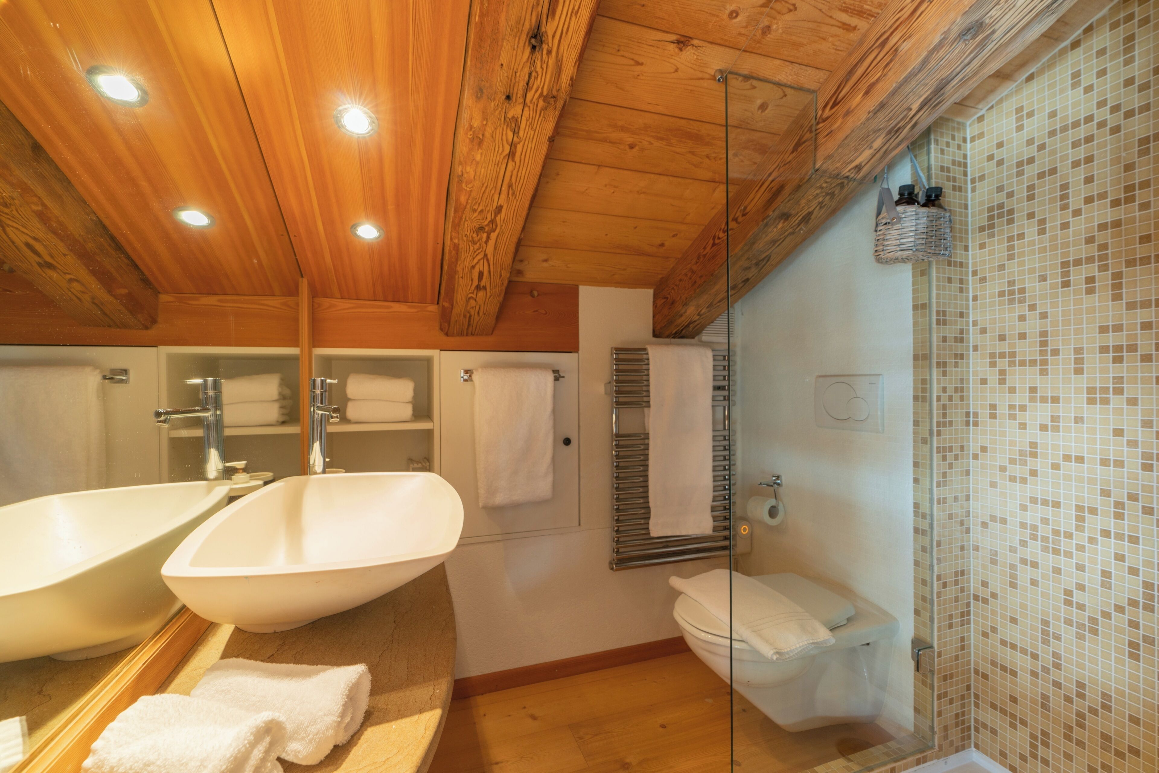Une salle de bain avec un plafond en bois, deux lavabos, des toilettes et un espace douche.