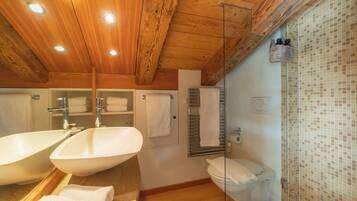 Une salle de bain avec un plafond en bois, deux lavabos, des toilettes et un espace douche.