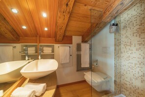 Ein Badezimmer mit Holzboden, zwei Waschbecken, einer Toilette und einer Duschkabine.