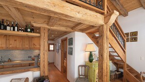 Interior em madeira com escada, área de jantar e cozinha com armários de madeira.