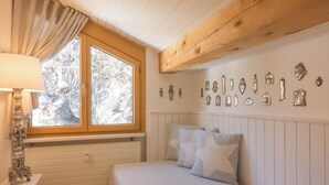 Een slaapkamer met een bed, een raam met gordijnen, een muur met decoratieve objecten en een houten plafond.