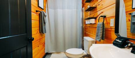 Un baño pequeño con inodoro, lavamanos y cortina de ducha.