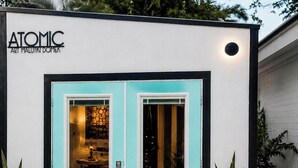 A modern building with a teal door, potted plants, and a gravel pathway. - THE ATOMIC ART MALUTKI DOMER™  HGTV Artist-Designed Tiny House Retreat Sleeps 4 (Fort Myers)