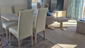 Una sala de estar moderna con comedor, un sofá, un televisor y una mesita.