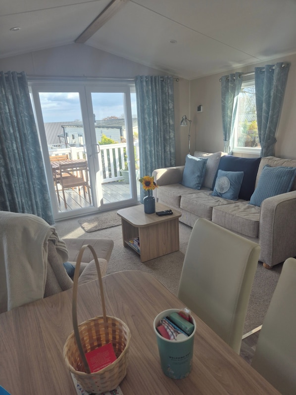 Un salon comprenant un canapé, une table basse et une table à manger avec des chaises. Il y a également un balcon avec vue sur l’extérieur.