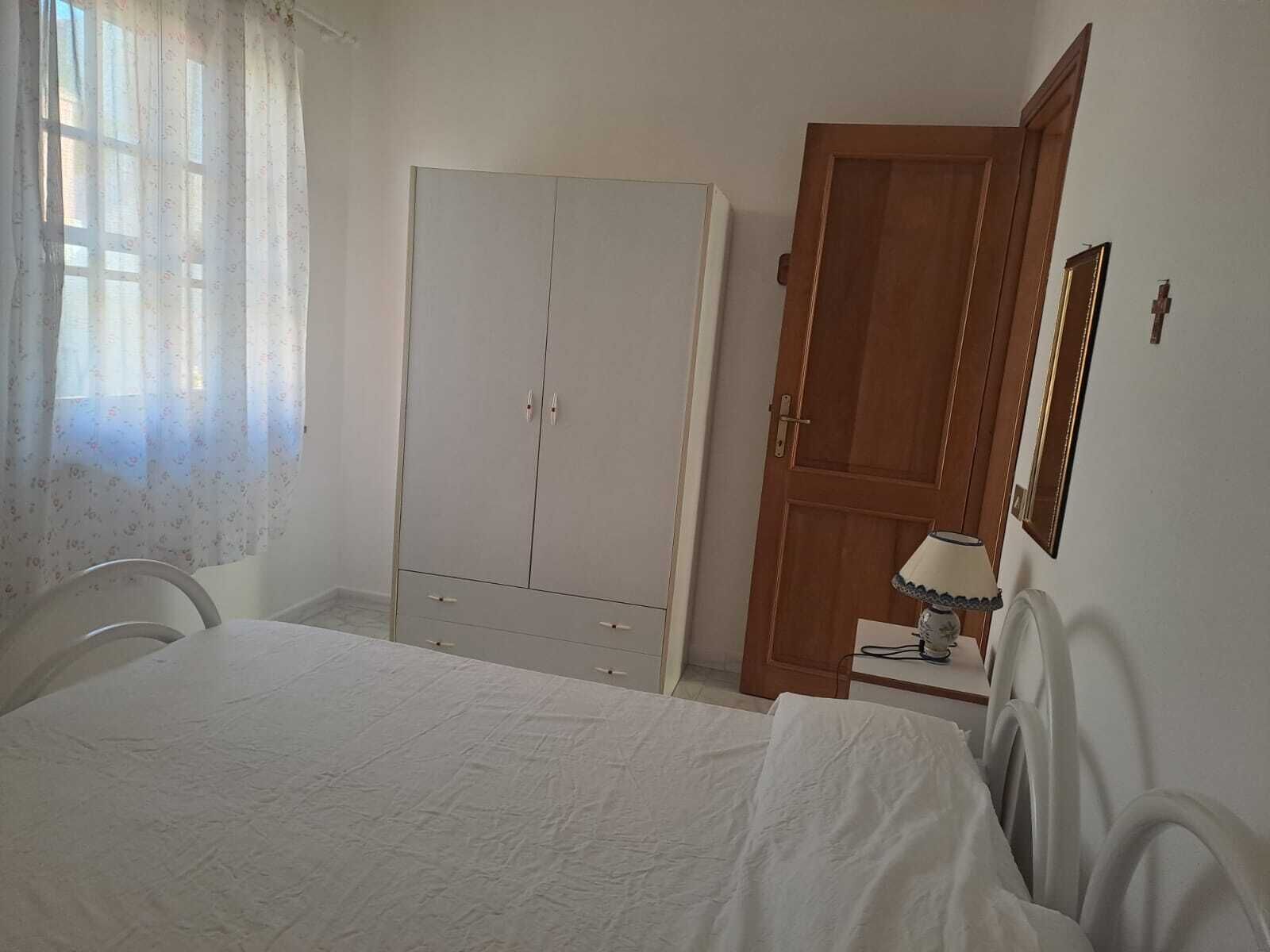 Ein Schlafzimmer mit Bett, Schrank, Holztür, Lampe und Spiegel.