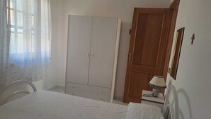 Ein Schlafzimmer mit Bett, Schrank, Holztür, Lampe und Spiegel.