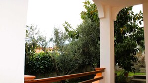 Ein Balkon mit Holzgeländer, einer Steinmauer und Grünpflanzen.