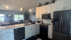 A modern kitchen with white cabinets, stainless steel appliances, and pendant lighting. - Tropical Oasis, 3 Bedroom house with pool. (Palm Bay)