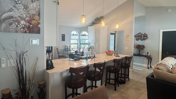 A modern kitchen with a central island, bar stools, and pendant lighting. - Tropical Oasis, 3 Bedroom house with pool. (Palm Bay)
