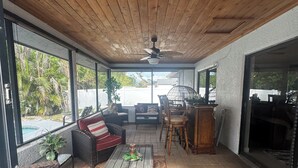 A covered patio area with wicker furniture, a ceiling fan, and a view of a swimming pool. - Tropical Oasis, 3 Bedroom house with pool. (Palm Bay)
