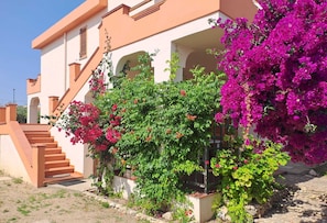 A building with a staircase, arches, and flowering plants. - Casa Giovanna - Villa (La Caletta)