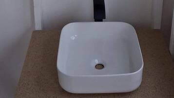 A white rectangular sink with a black faucet on a beige countertop.