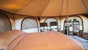 A tent with a bed, chairs, and a shelf with items. - Journey South West Tent 3 (Farmington)