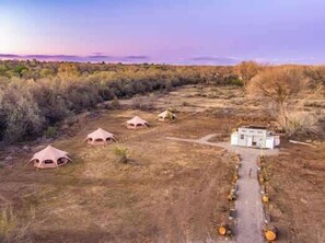 Un camping con varias tiendas en forma de cúpula y un edificio central, rodeado de vegetación seca.