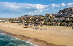 Um resort costeiro com villas na praia, uma praia de areia e vista para o oceano.