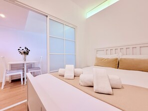 Ein Hotelzimmer mit einem Bett, einem kleinen Tisch mit Stühlen und einem Fenster mit satiniertem Glas.