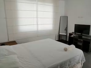 A hotel room with a bed, a television, a mirror, and a dresser. - De-stress in the tranquility of the beautiful bay (Pucusana)