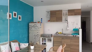 A compact living space with a kitchenette, a dining area with a table and chairs, and a blue accent wall. - De-stress in the tranquility of the beautiful bay (Pucusana)