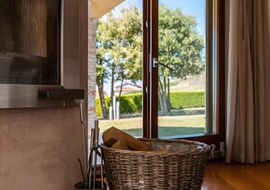 Un panier en osier contenant divers objets, une fenêtre donnant sur un paysage verdoyant et une porte avec une poignée.
