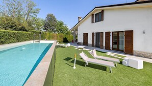 Une maison moderne dotée d’une piscine, d’un espace extérieur aménagé et d’une pelouse bien entretenue.