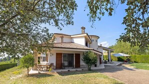 Une maison à deux étages dotée d’un patio, d’un espace extérieur aménagé et couvert, et d’une pelouse bien entretenue.