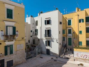 Un carrer estret amb edificis que tenen balcons i persianes.