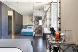 Een moderne hotelkamer met een bed, een badkamer met een marmeren wand, en een ontbijtbalk met een glas sinaasappelsap.