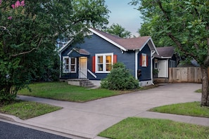 Ein eingeschossiges Haus mit Veranda, Garage und gepflegtem Rasen.