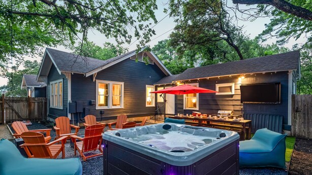 A backyard with a hot tub, outdoor seating, and a barbecue area.