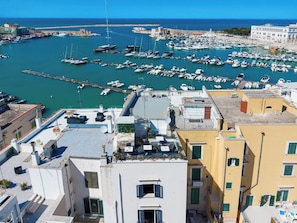 A marina with numerous boats docked, a clear blue sky, and buildings with balconies overlooking the water. - Harbour - Luxury Room Pearl (Trani)