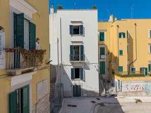 Una calle estrecha con edificios que tienen balcones y contraventanas.