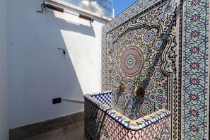 Pared de azulejos con diseños intrincados y una pequeña fuente.
