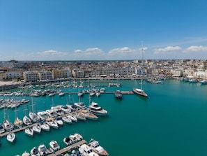 A marina with numerous boats docked, surrounded by a coastal cityscape with buildings. - Harbour - Luxury Room Pearl (Trani)