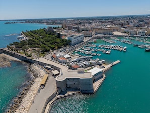 An aerial view of a coastal town with a historic fort, marina, and surrounding buildings. - Harbour - Luxury Room Pearl (Trani)