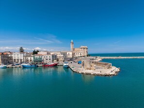 Un pueblo costero con edificios históricos, una torre destacada y un puerto con barcos.