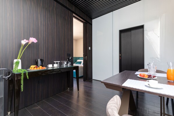 Una cocina moderna con armarios de madera oscura, una mesa de comedor con un mantel individual blanco y un espacio para el desayuno que incluye frutas, una cafetera y un vaso de zumo de naranja.