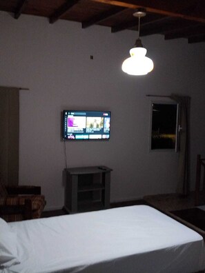 A room with a bed, a television mounted on the wall, a window, and a door. - mar de cobo refugio entre el lago y el mar (Parque Lago)