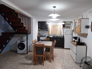 A compact kitchen with a dining area, a washing machine, and a staircase. - mar de cobo refugio entre el lago y el mar (Parque Lago)