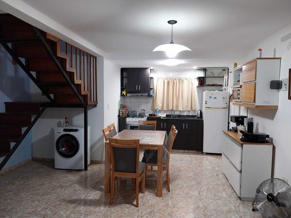 A compact kitchen with a dining area, a washing machine, and a staircase.
