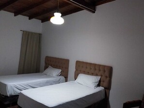 A room with two single beds, a wooden ceiling, and a hanging light fixture. - mar de cobo refugio entre el lago y el mar (Parque Lago)