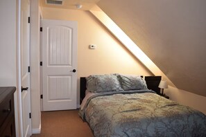 Une chambre à coucher avec un lit, une porte, un thermostat et une lampe.