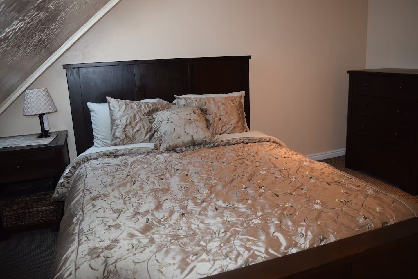 Un dormitorio con cama, mesita de noche, lámpara y cómoda.